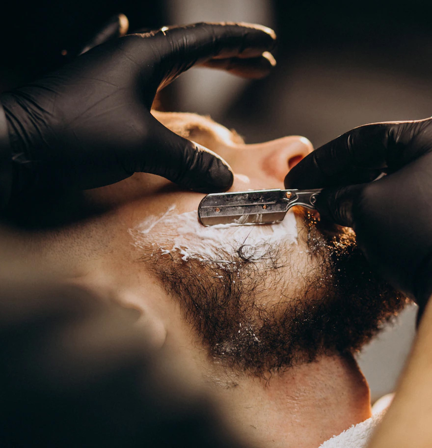 Barbeiro fazendo a barba do cliente
